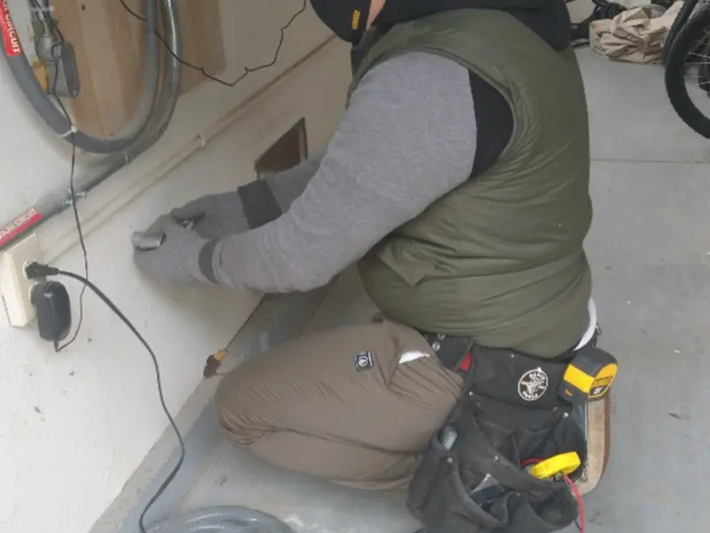 Electrician performing outlet wiring in a Iosco garage